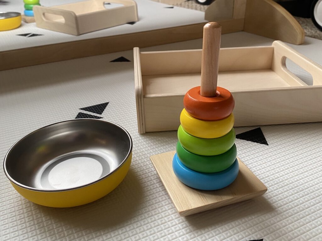 Completed wooden rainbow stacker next to a stainless steel bowl and wooden tray