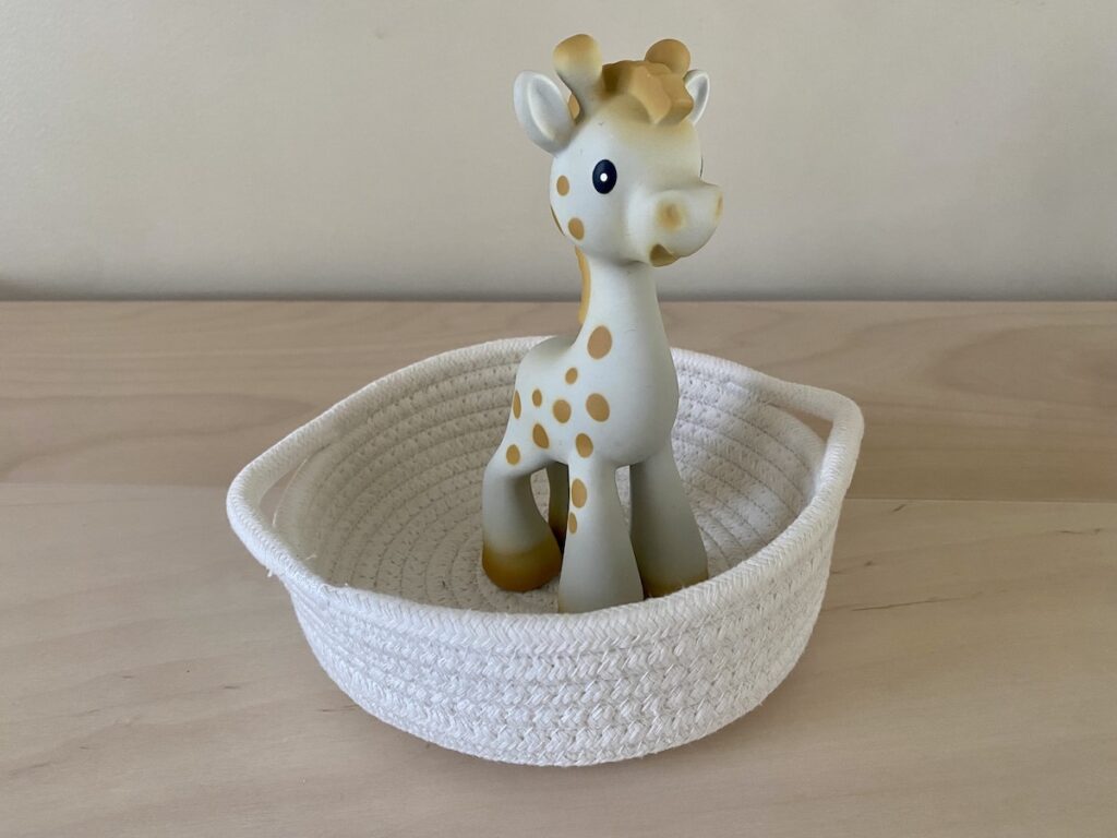A rubber teething giraffe in a cotton basket